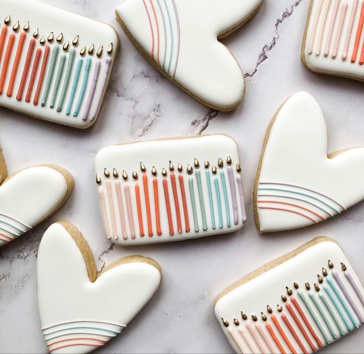 decorated cookies are arranged in the shape of combs and hearts on a marble surface