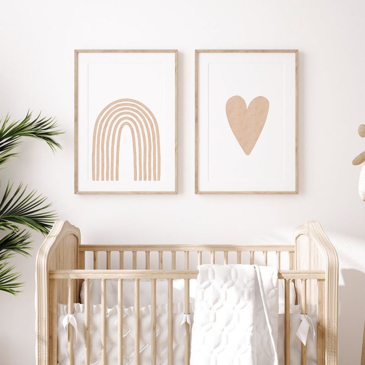 two framed pictures above a crib in a baby's room, one with a heart and the other with a rainbow