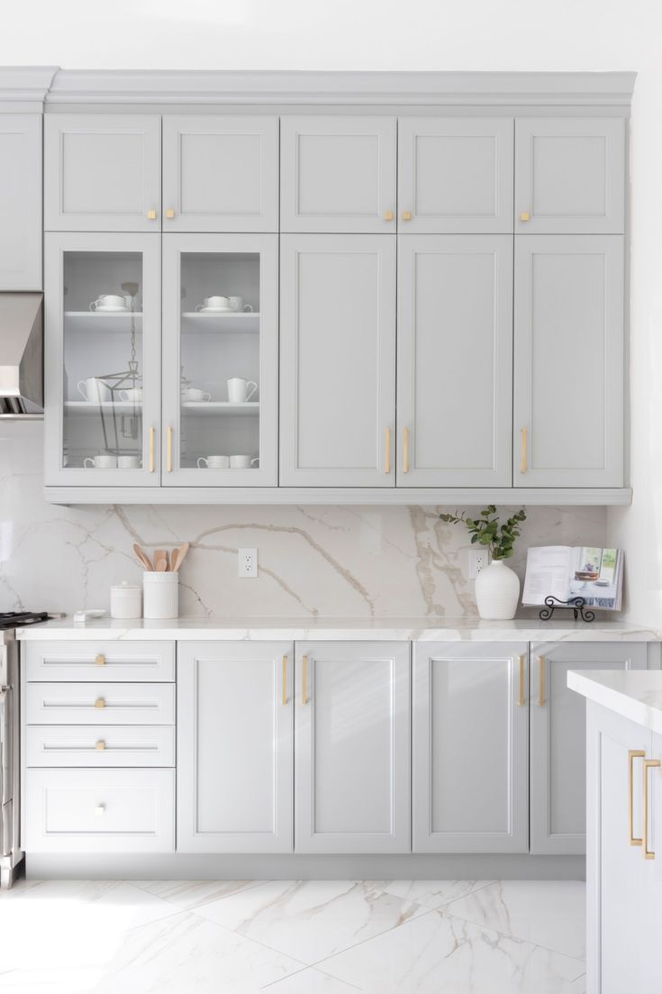 an all white kitchen with marble counter tops and gold trim on the cabinet doors is pictured in this image