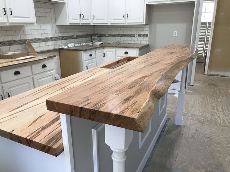 a kitchen with white cabinets and wooden counter tops