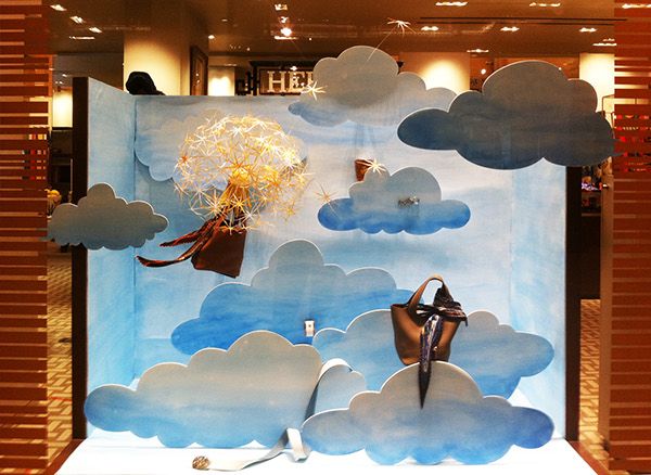 a window display with clouds and a woman holding a basket