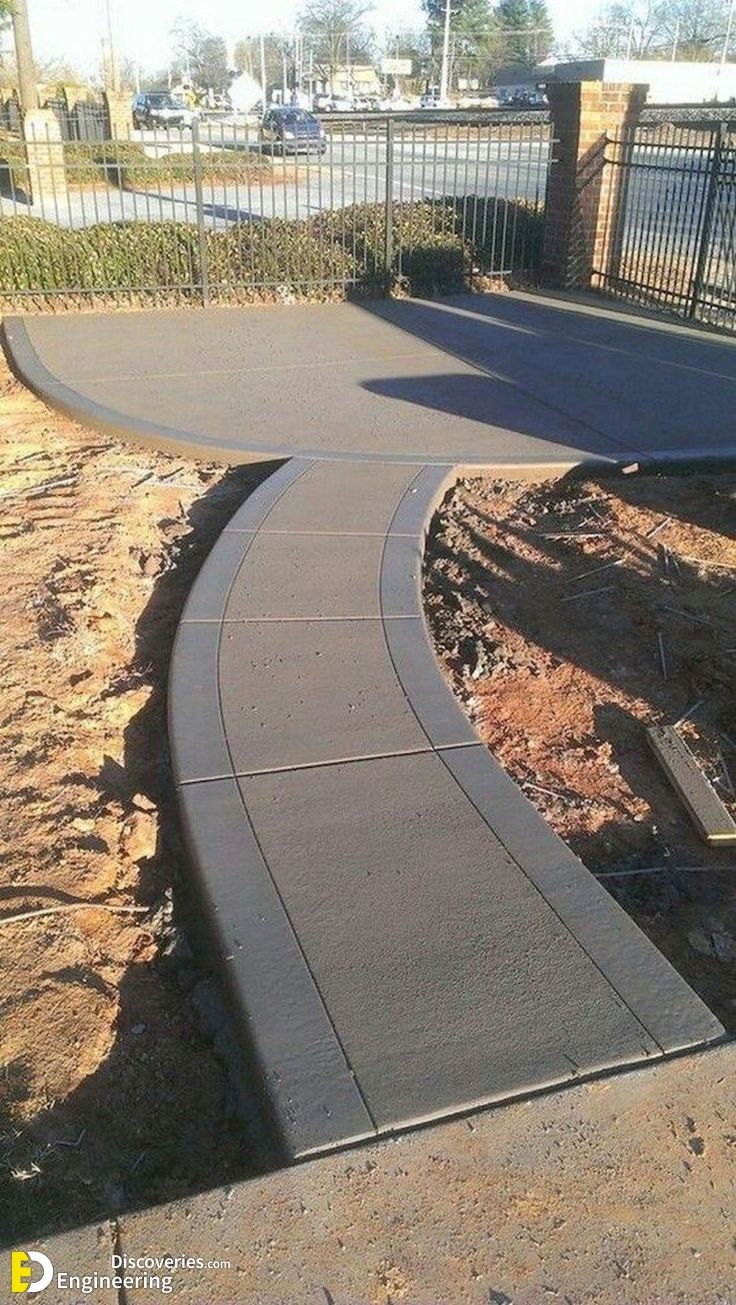 a curved walkway in front of a fence