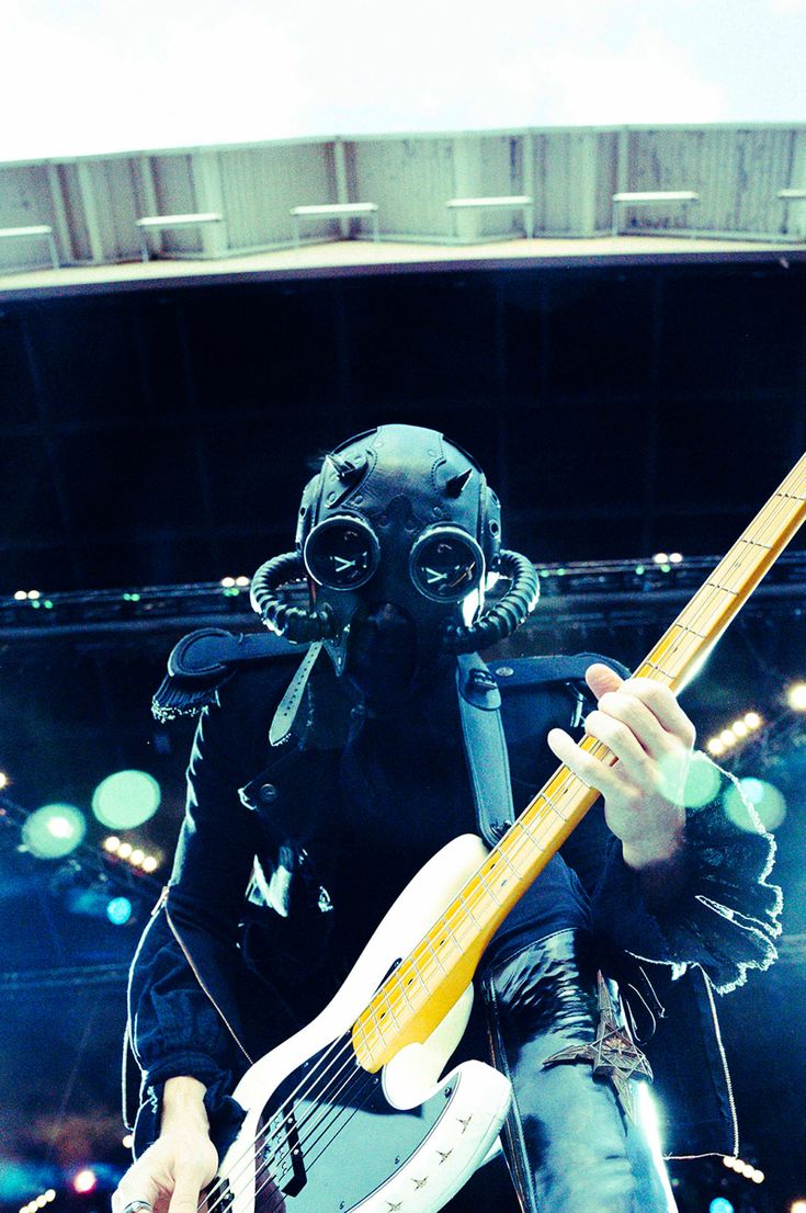 a man wearing a gas mask playing an electric guitar