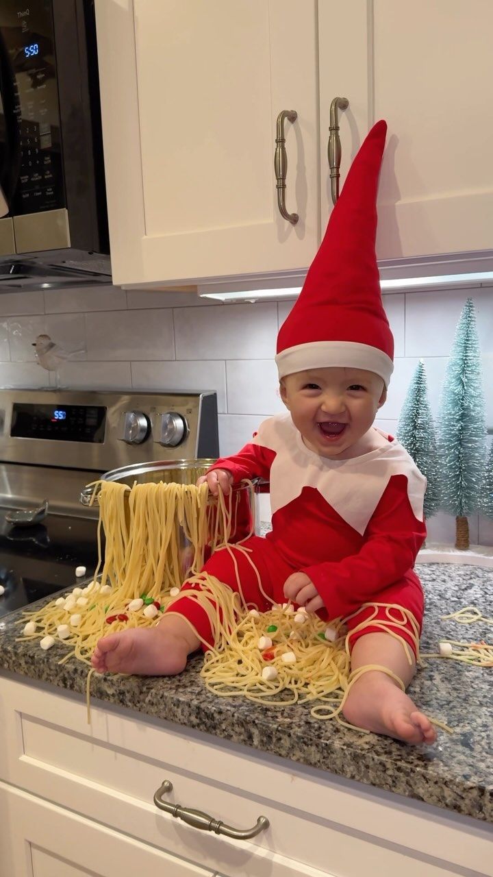 a baby dressed as an elf sitting on top of a counter