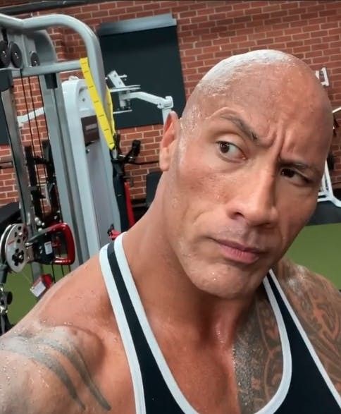 a bald man in a black tank top is posing for the camera at a gym