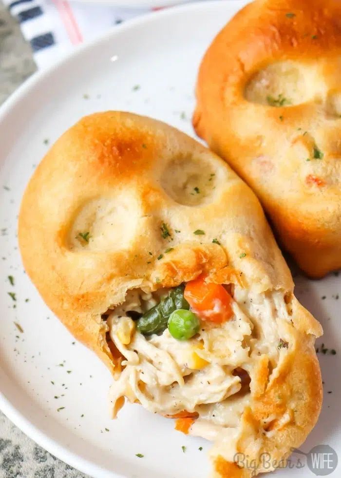 two chicken pot pies on a plate with one cut in half to show the filling