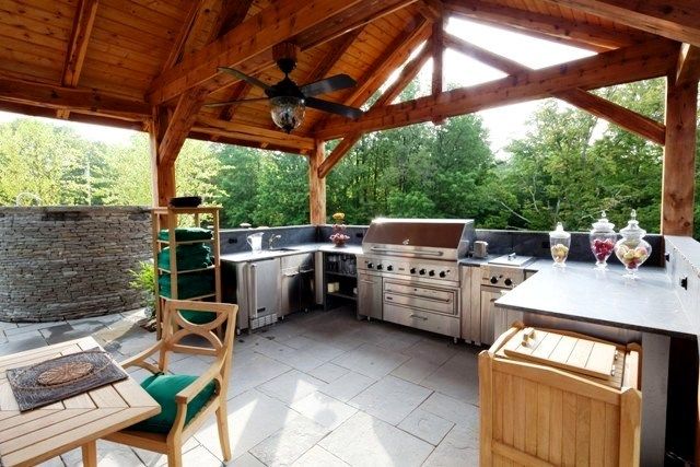 an outdoor kitchen with grill, sink and table