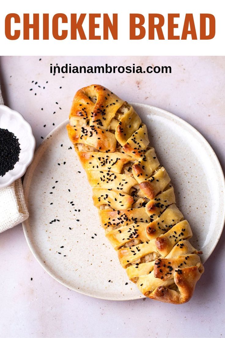 this chicken bread is on a white plate with black sesame seeds and seasoning next to it