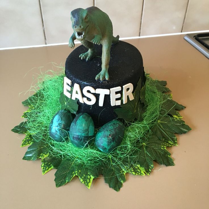 a cake decorated with green grass and an animal on top that says easter next to eggs