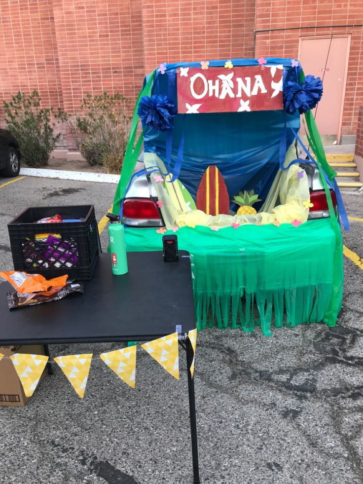 a table that has some items on it in front of a building with cars parked nearby