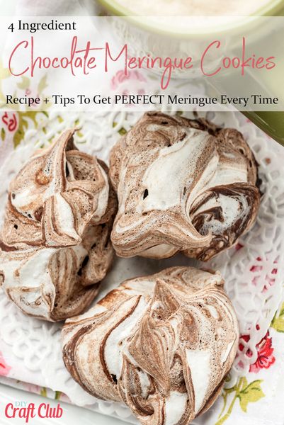 three chocolate meringue cookies on a plate with a cup of coffee in the background