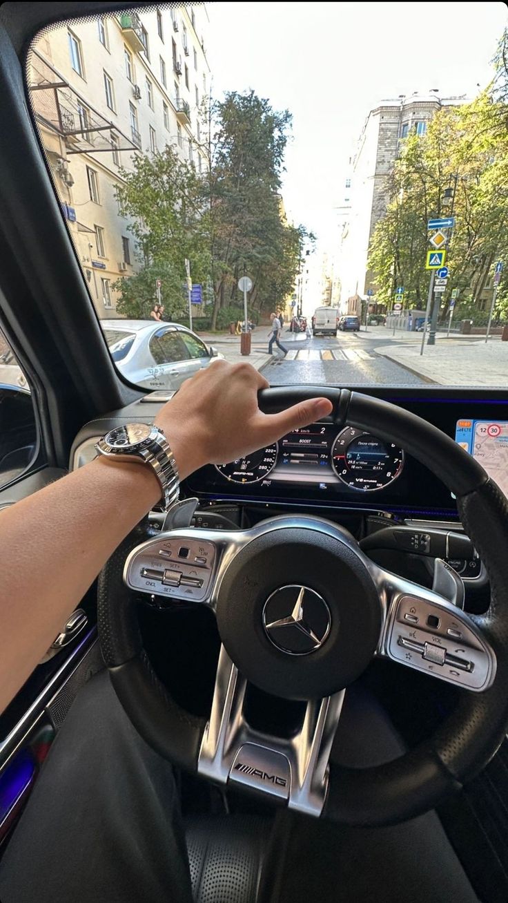 a person driving a car with their hand on the steering wheel