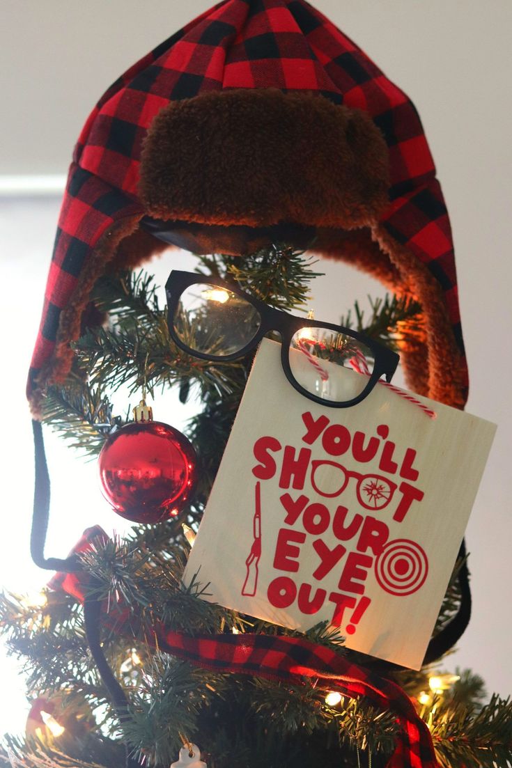 a hat and eyeglasses are on top of a christmas tree with a sign that says, you'll shoot your eye out