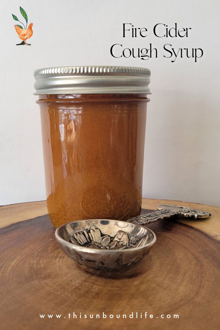 a wooden table topped with a glass jar filled with liquid next to a metal spoon