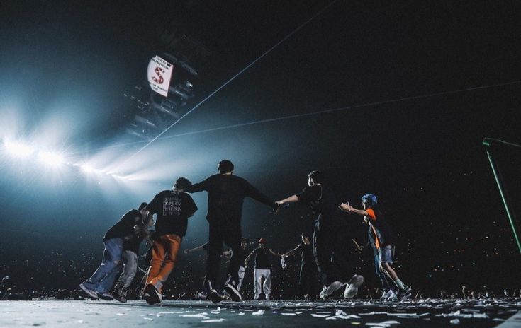 a group of people standing on top of a stage with their hands in the air