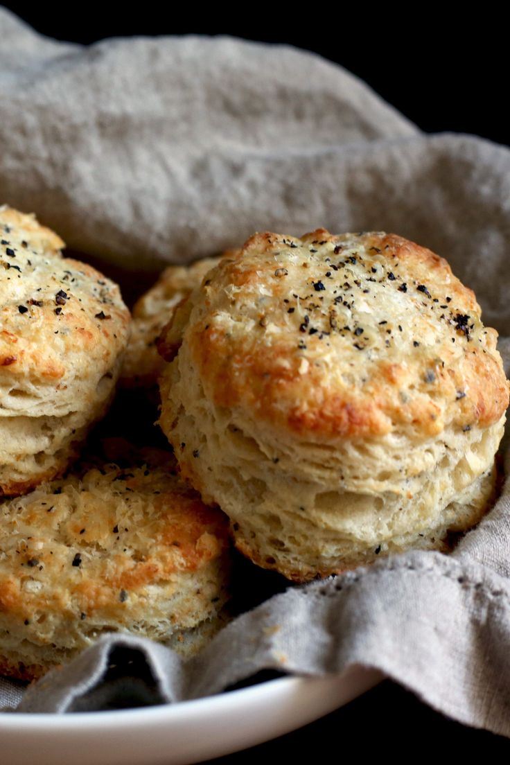 some biscuits are sitting in a white bowl on a gray cloth and black tablecloth