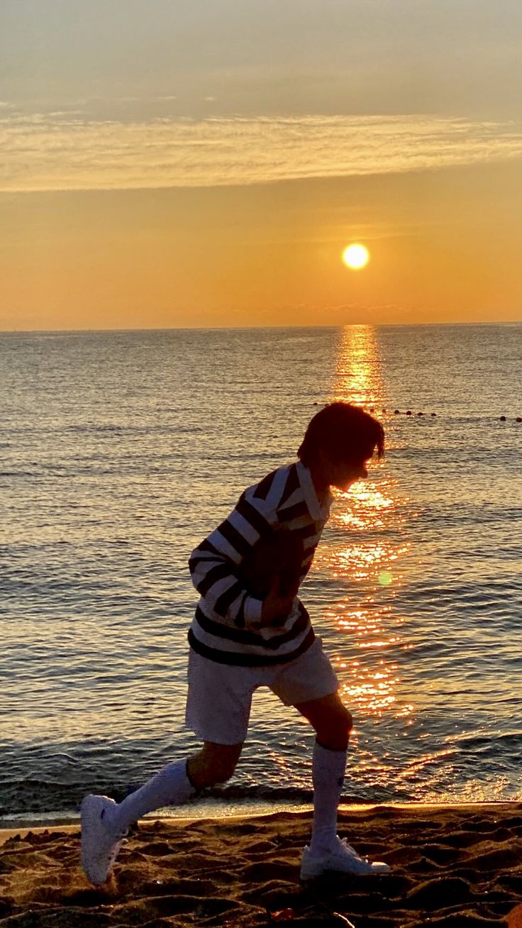 a man running on the beach at sunset with his feet in the sand and water