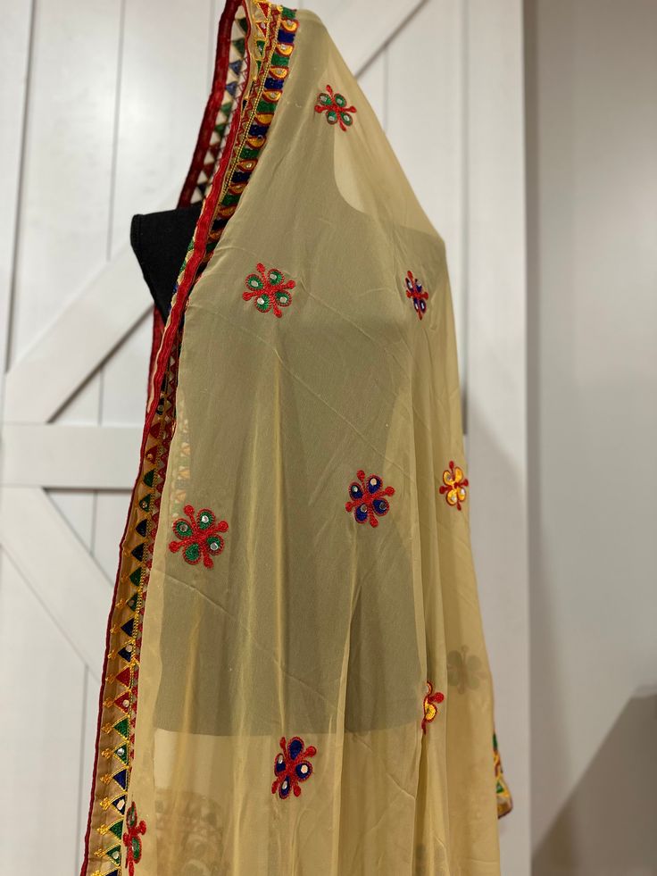 Enhance your Navaratri look with our Navaratri Dupatta in beige. This festive wear dupatta features stunning mirror and thread work, and is made of high-quality georgette fabric. Elevate your traditional attire and make a statement with this elegant dupatta. Bohemian Georgette Saree For Festivals, Traditional Kundan Dupatta For Navratri, Traditional Cream Lehenga With Gota Work, Traditional Georgette Wear With Gota Work For Festivals, Navratri Festive Dupatta With Dori Work, Anarkali Dupatta With Mirror Work For Puja, Festive Navratri Dupatta With Dori Work, Festive Dori Work Dupatta For Navratri, Bohemian Georgette Dupatta With Traditional Drape