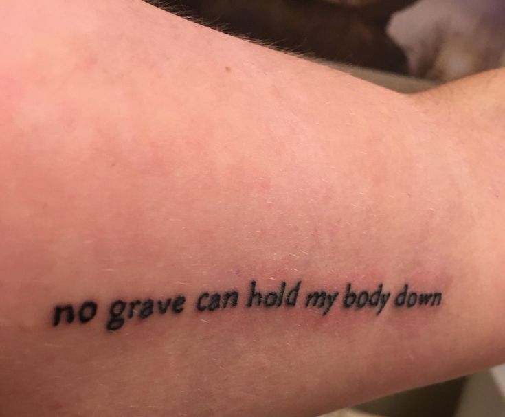 a person with a tattoo saying no grave can hold my body down on their arm