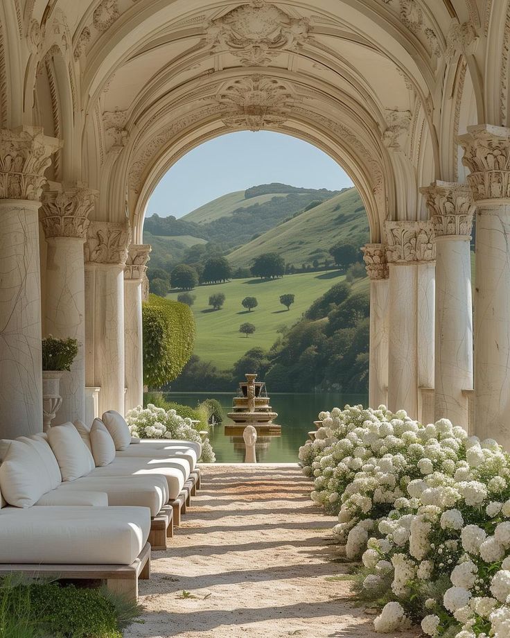 an archway leading to a garden with white flowers in the foreground and a fountain on the other side