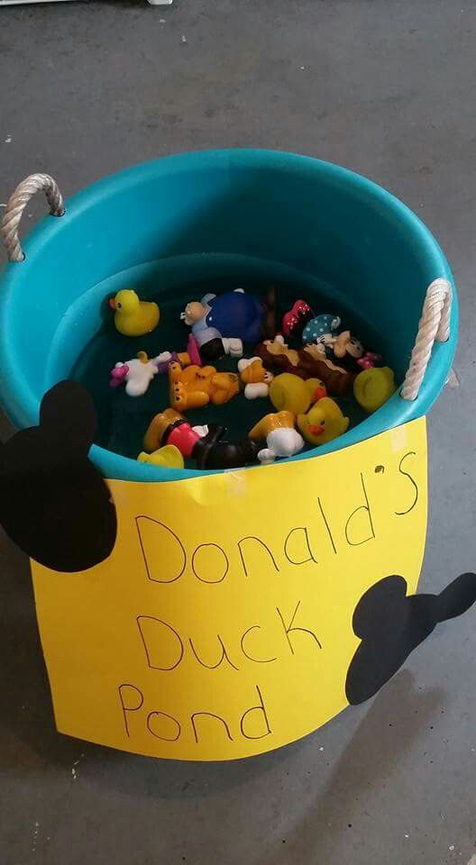 a bucket filled with lots of toys sitting on top of a cement floor next to a sign that says donald's duck pond