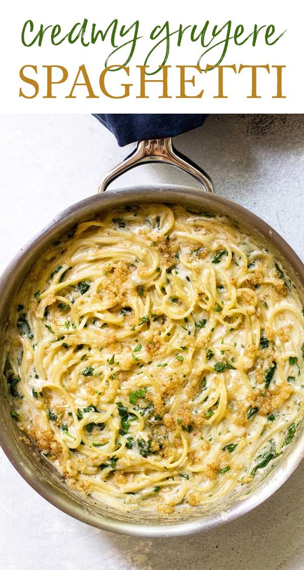 a pan filled with pasta and spinach on top of a table