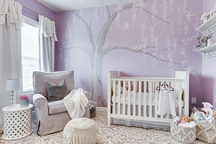 a baby's room with a tree painted on the wall and furniture in the corner