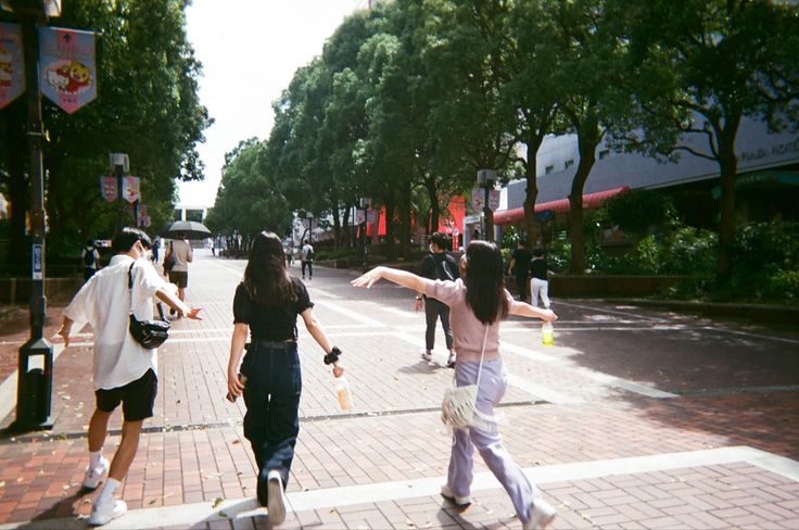 two women are walking down the street with their arms in the air and one woman is holding her arm out