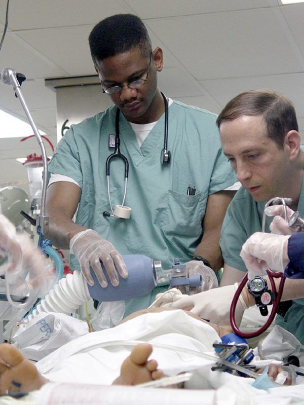 two men in scrubs tending to a baby