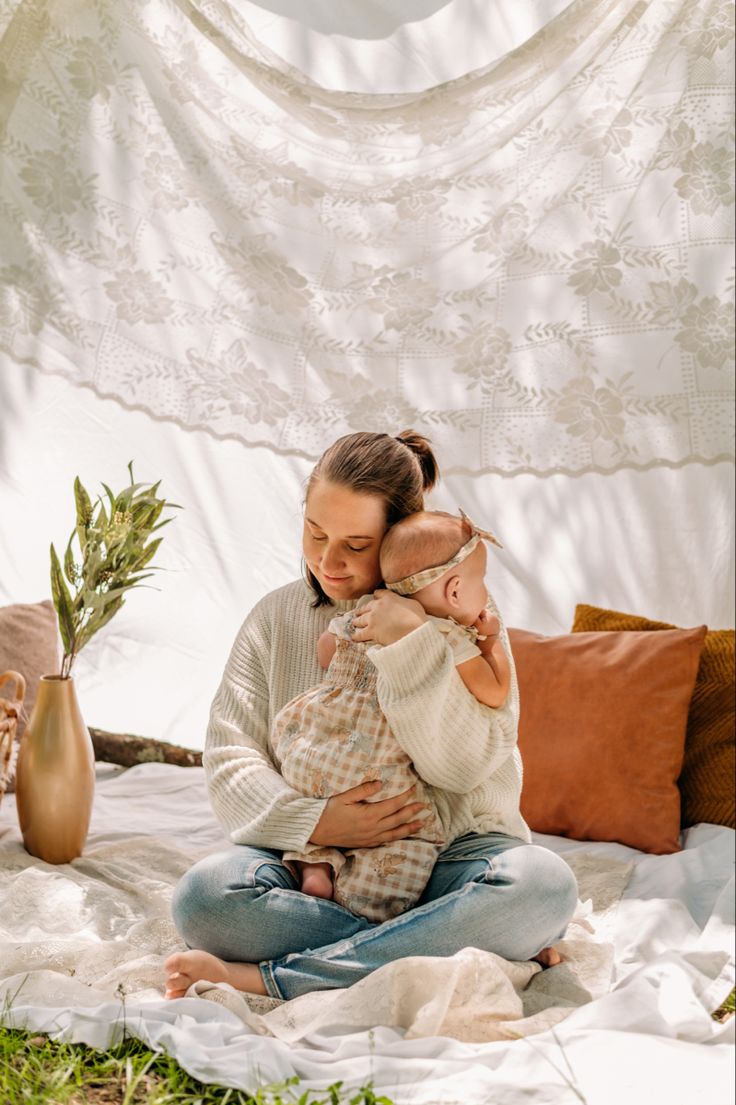 a woman sitting on top of a bed holding a baby