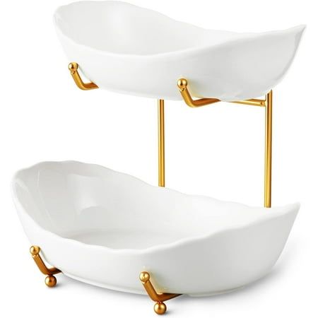 two white bowls with gold handles on stands