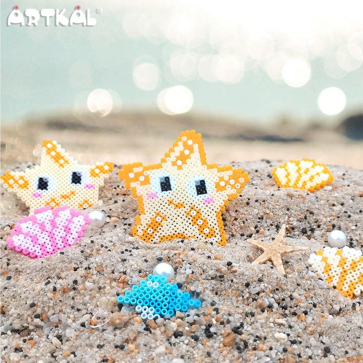 three little starfishs are on the sand with pearls and beads in their mouths