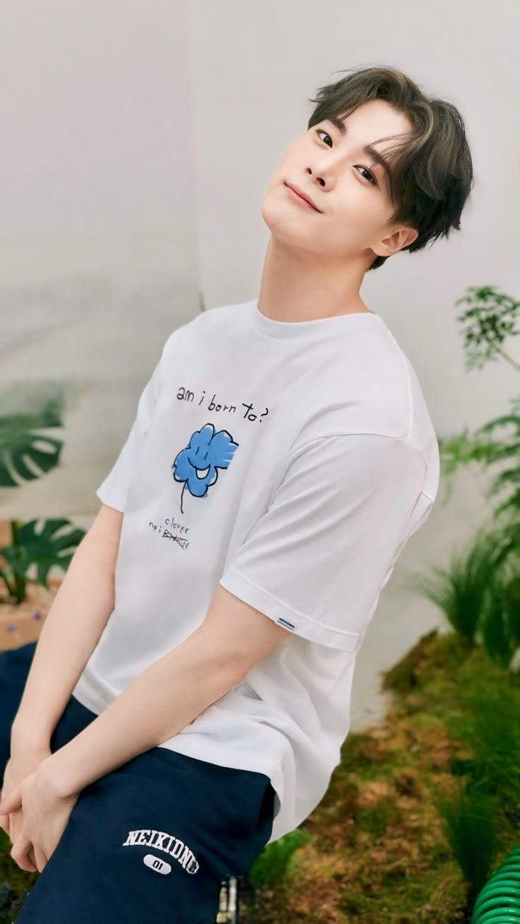 a young man sitting on top of a wooden bench wearing a white t - shirt