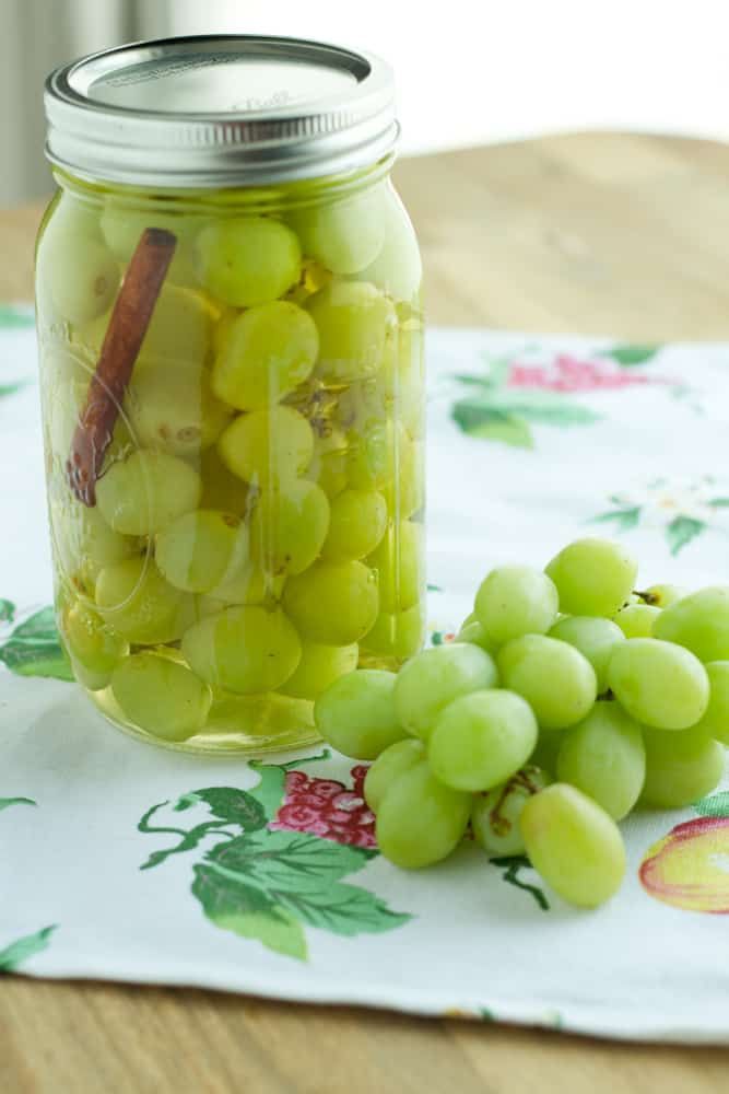 green grapes are in a glass jar on a table