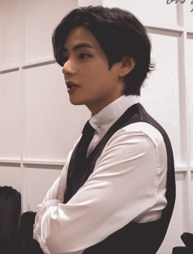 a young man wearing a white shirt and black tie standing in front of a wall