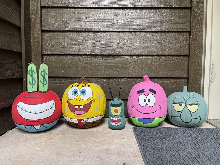 five painted pumpkins sitting in front of a door