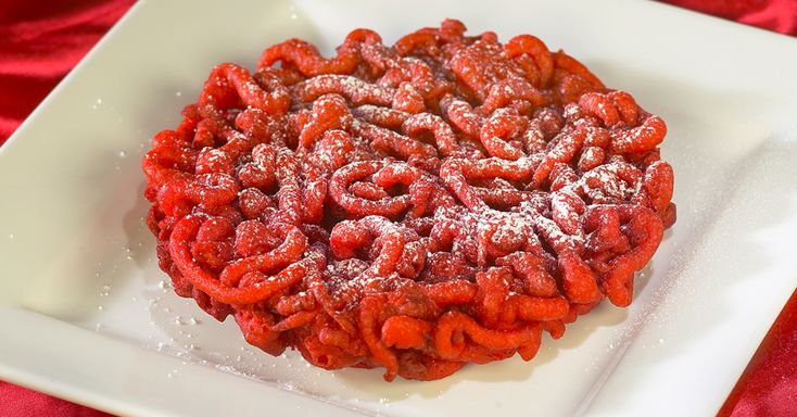 a white plate topped with red powdered donuts on top of a red table cloth