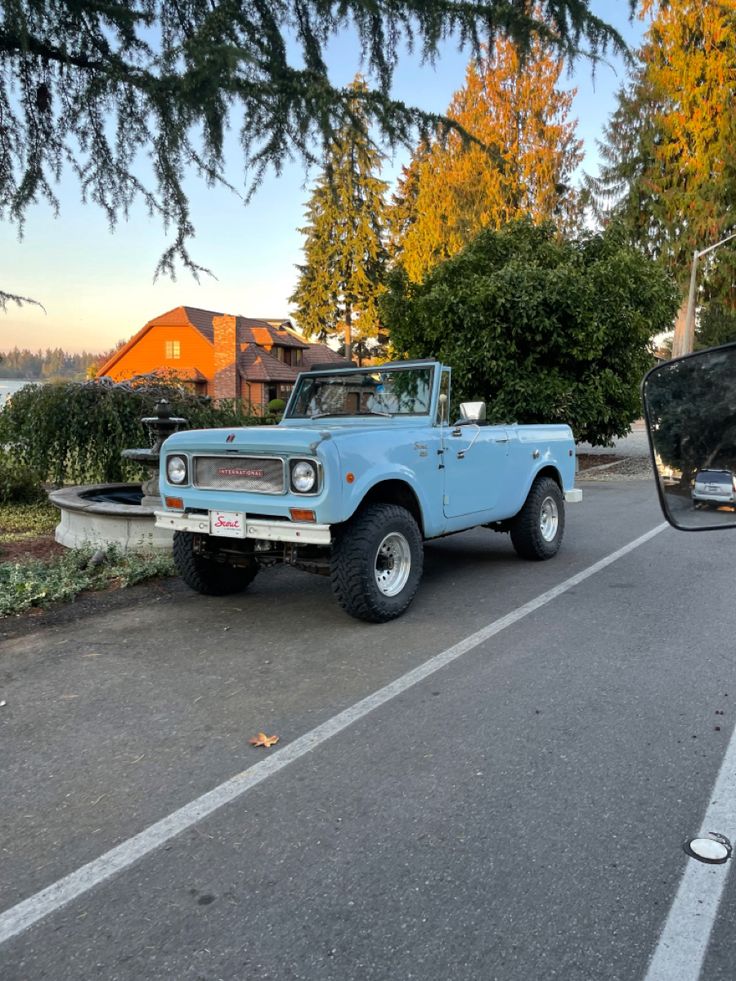 an old blue truck is parked on the side of the road next to some trees