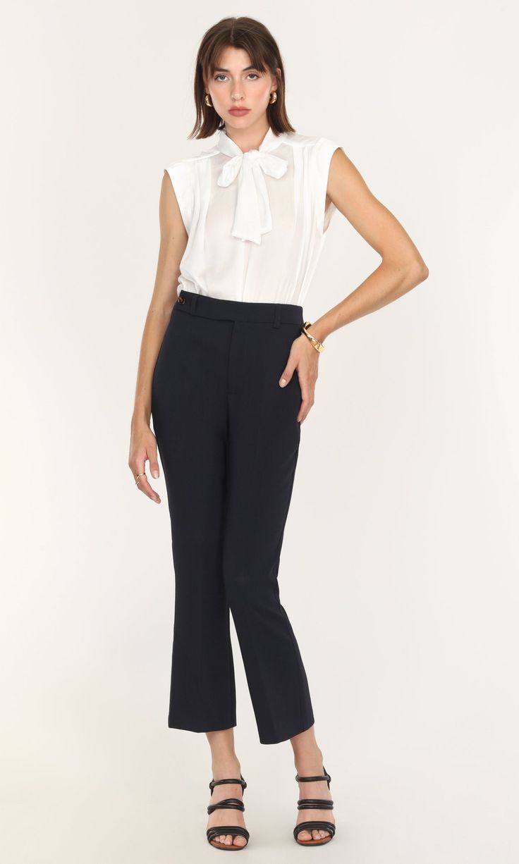 This sleeveless blouse was created for both tailored and casual looks. A modified version of the Edna Neck Tie Blouse, this high-collared piece can still be tied and styled in multiple ways. The tank top feel is comfortable and suitable for adjusting easily between formal and informal meetings. Wearing a blazer or coat over feels even easier without having to adjust sleeves to match. Tie bow blouse Sleeveless Satin Cotton Imported 100% Polyester Length: 24" Chest: 20 1/4" Hand wash in cold water Chic Stretch Blouse For Business Casual, Chic Stretch Blouse For Work, Chic Sleeveless Blouse For Office, Chic Sleeveless Office Blouse, Fitted Tie Neck Top For Workwear, Elegant Sleeveless Tops For Business Casual, Classic Sleeveless Blouse For Work, Sleeveless Business Casual Blouse, Sleeveless Blouse For Business Casual