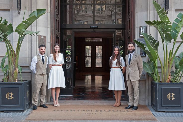 a group of people standing in front of a building with planters on either side