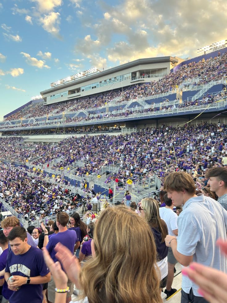 a crowd of people standing around each other at a soccer game in a stadium with the sun shining down on them