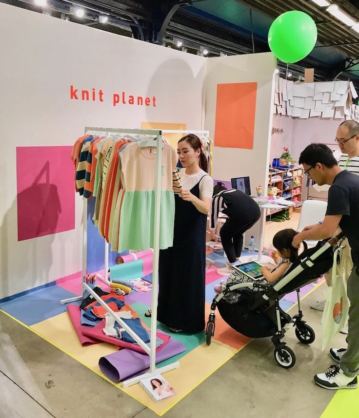 people are looking at clothes on display in a room with colorful walls and flooring