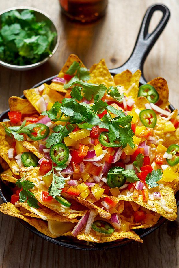 a bowl full of nachos with salsa and cilantro on the side