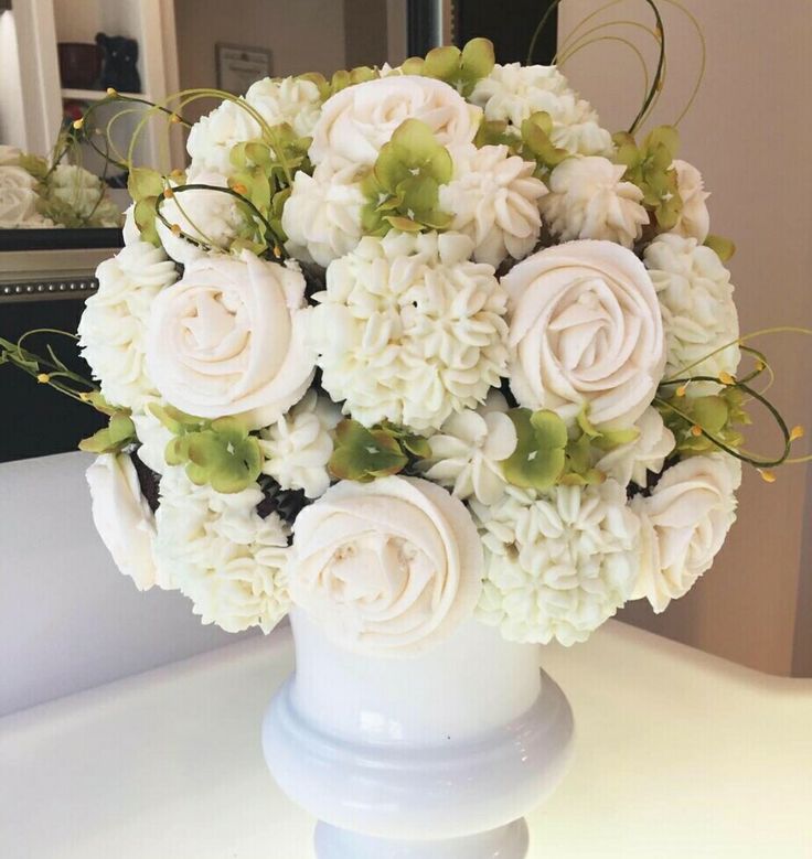 a vase filled with white flowers on top of a table next to a mirror and a dresser