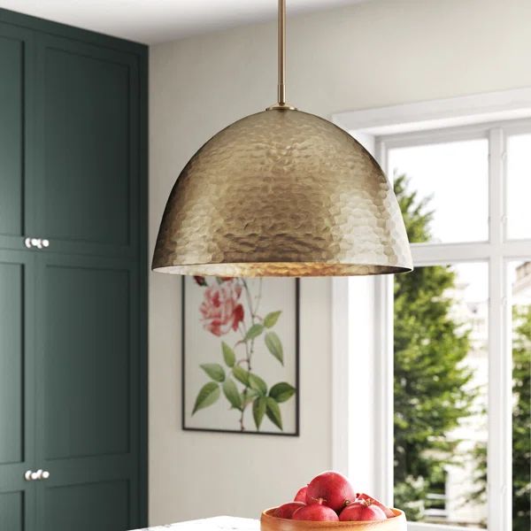 a kitchen with green cabinets and an island in front of a window that has a gold dome light hanging over it