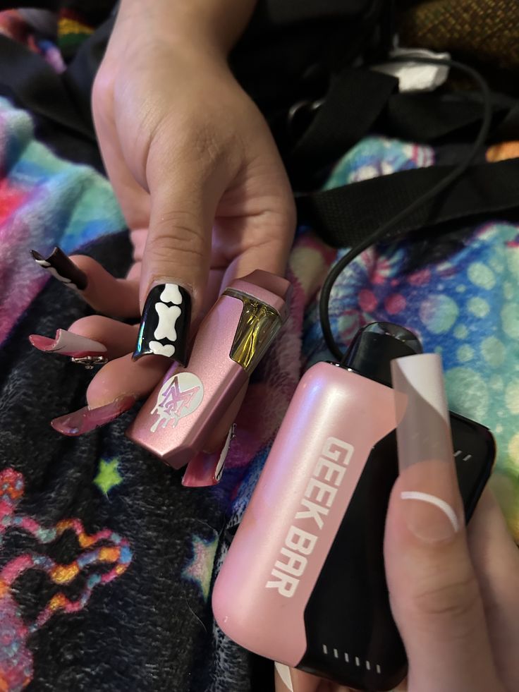 a person with pink and black nail polish on their nails, holding onto a lighter