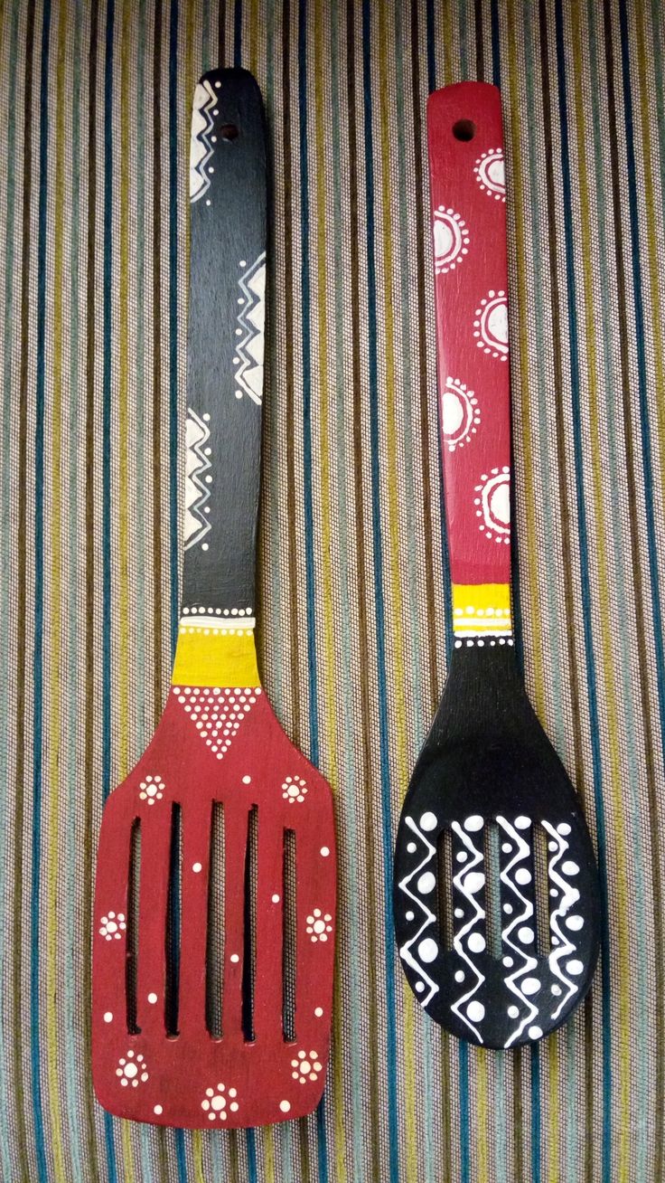 two wooden utensils sitting on top of a striped cloth covered table next to each other