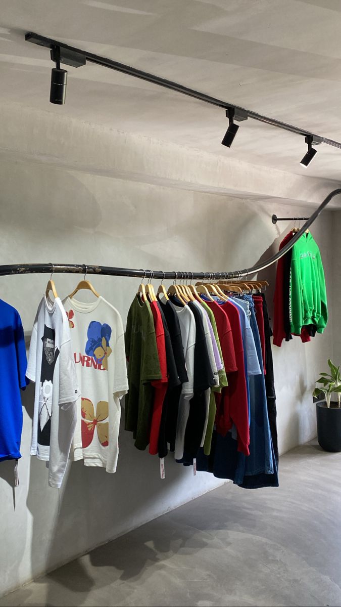 there are many t - shirts hanging on the clothes line in this room, and one is green