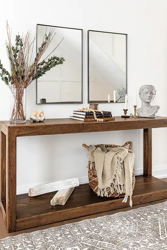 a console table with two mirrors above it and vases on the top, along with other decorative items