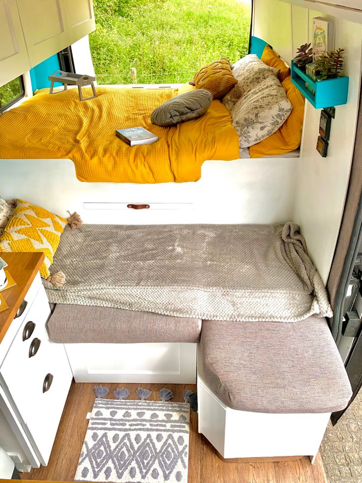 the interior of a small camper with a bed and storage area on the side